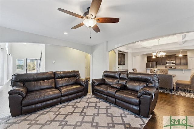 living room featuring beamed ceiling, coffered ceiling, ceiling fan with notable chandelier, and light wood-type flooring