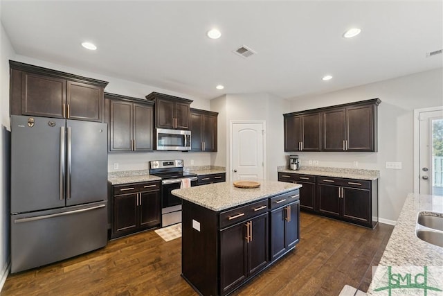 kitchen featuring a kitchen island, appliances with stainless steel finishes, dark hardwood / wood-style flooring, dark brown cabinetry, and light stone countertops