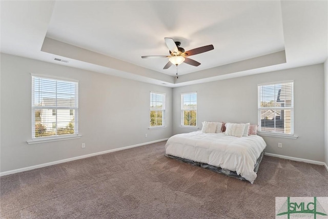 bedroom with ceiling fan, carpet flooring, and a tray ceiling