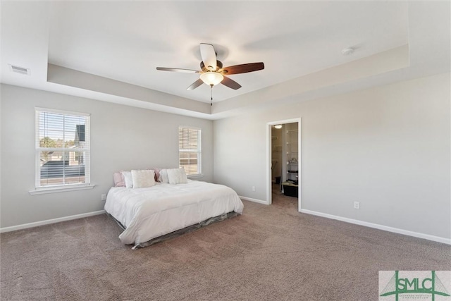 bedroom featuring carpet flooring, a raised ceiling, and multiple windows