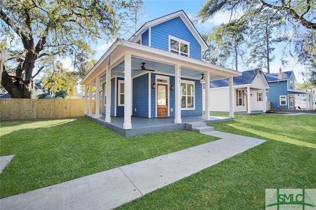 rear view of property featuring ceiling fan, covered porch, and a lawn