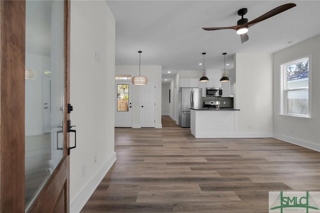 unfurnished living room featuring ceiling fan, plenty of natural light, and wood-type flooring