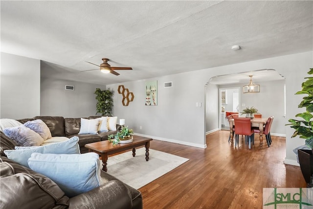 living room with ceiling fan, dark wood-type flooring, and a textured ceiling