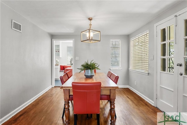 dining area with dark wood-type flooring and a chandelier