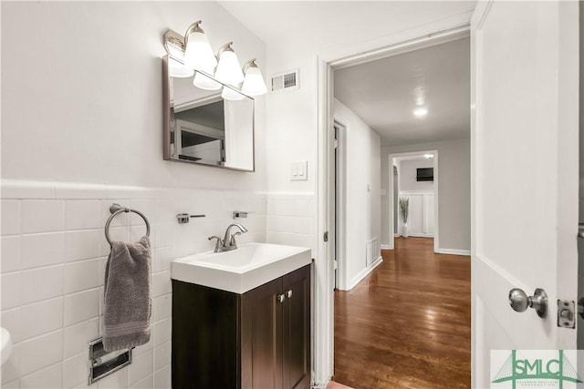 bathroom with vanity, wood-type flooring, and tile walls