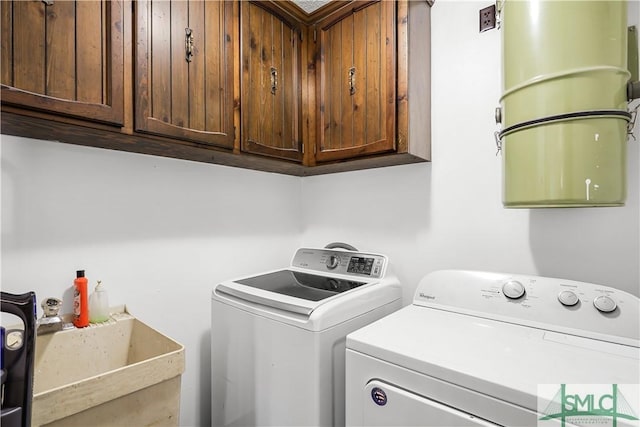 clothes washing area featuring sink, cabinets, and washer and dryer