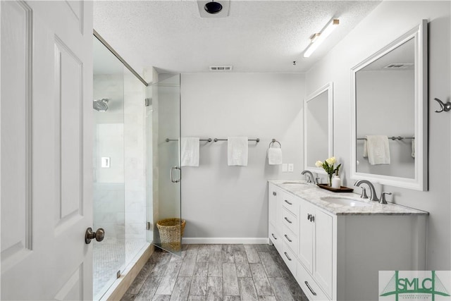 bathroom featuring vanity, a shower with shower door, and a textured ceiling