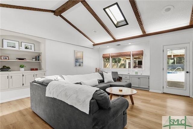 living room with a skylight, plenty of natural light, beam ceiling, and light hardwood / wood-style flooring