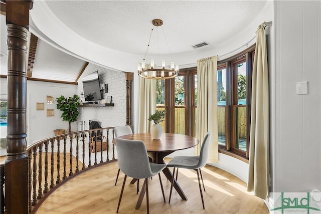 dining area with a textured ceiling, light hardwood / wood-style flooring, and a notable chandelier