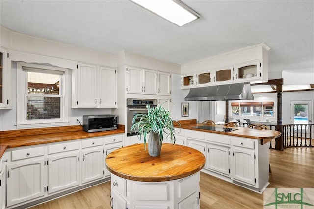 kitchen featuring white cabinetry, stainless steel appliances, butcher block counters, and a kitchen island