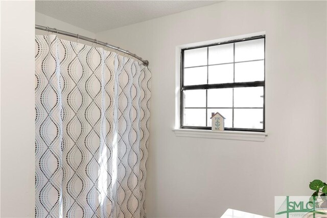 bathroom featuring curtained shower and a textured ceiling