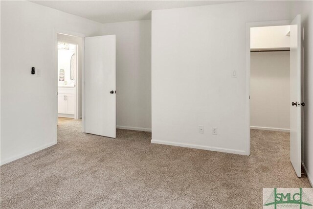 unfurnished bedroom featuring a spacious closet, light carpet, and a closet