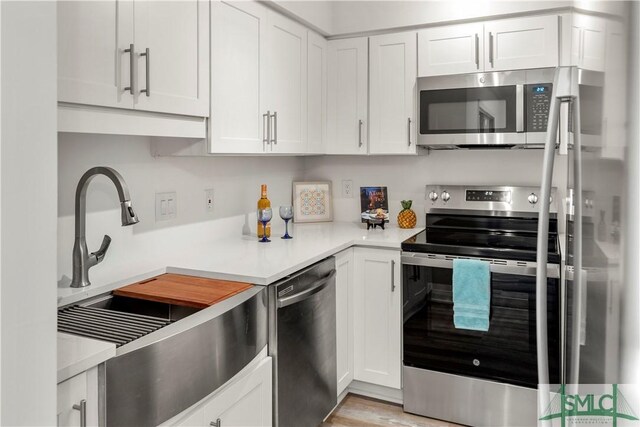 kitchen with sink, light hardwood / wood-style flooring, stainless steel appliances, and white cabinets