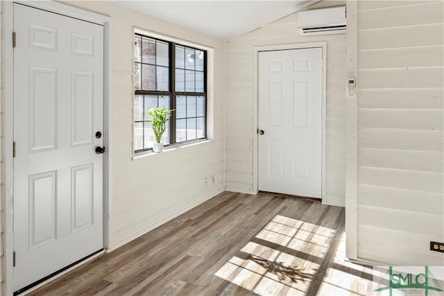 entrance foyer featuring vaulted ceiling, a wall unit AC, and light wood-type flooring