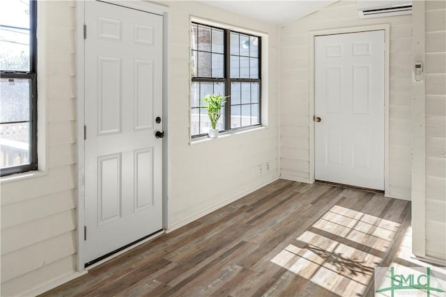 entrance foyer featuring lofted ceiling, wood-type flooring, and an AC wall unit