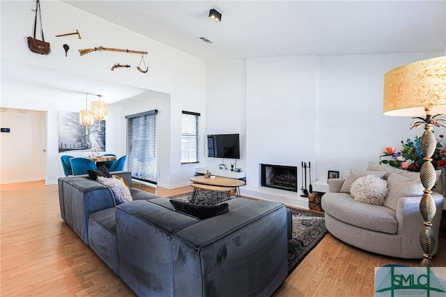 living room featuring an inviting chandelier, a high ceiling, and light wood-type flooring