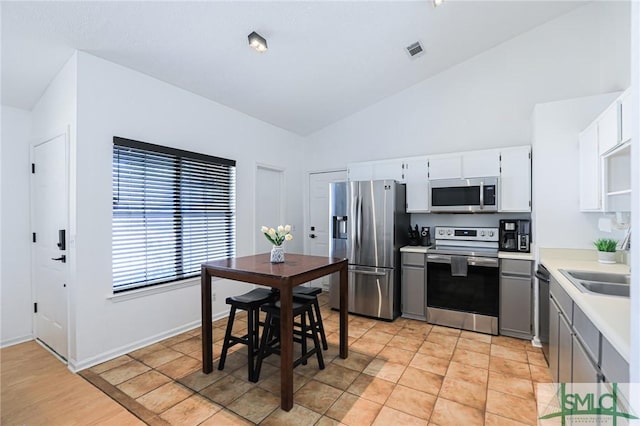 kitchen with sink, light tile patterned floors, gray cabinets, appliances with stainless steel finishes, and white cabinets