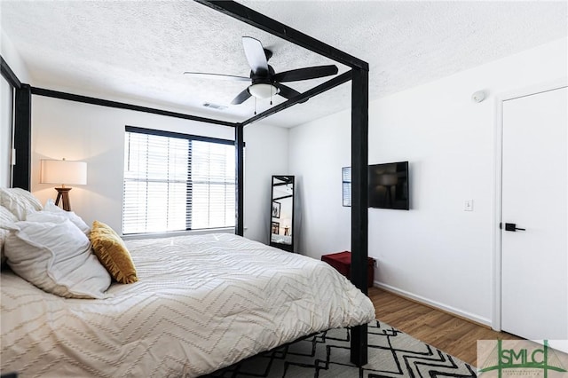 bedroom featuring ceiling fan, wood-type flooring, and a textured ceiling