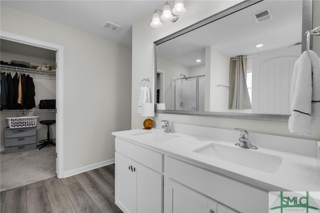 bathroom with wood-type flooring, vanity, and walk in shower