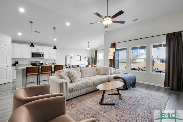 living room with ceiling fan, lofted ceiling, and light hardwood / wood-style floors