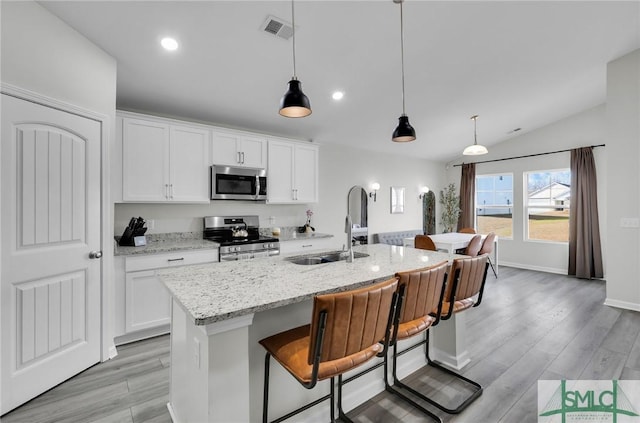 kitchen with stainless steel appliances, a kitchen island with sink, sink, and white cabinets