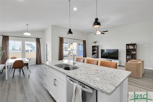 kitchen featuring an island with sink, sink, white cabinets, hanging light fixtures, and stainless steel dishwasher