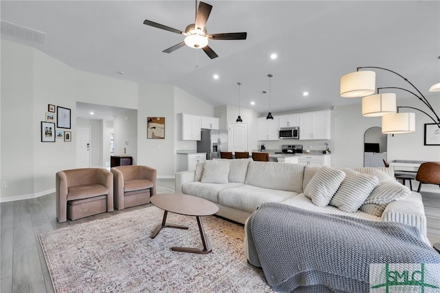 living room with vaulted ceiling, ceiling fan, and light wood-type flooring