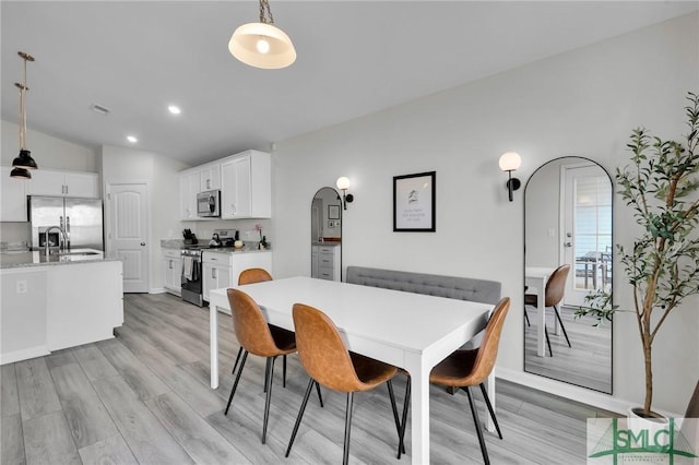 dining space with lofted ceiling, light hardwood / wood-style floors, and sink