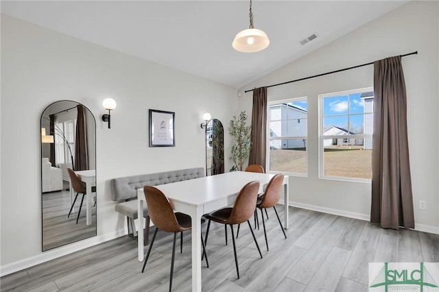 dining space with vaulted ceiling and light wood-type flooring