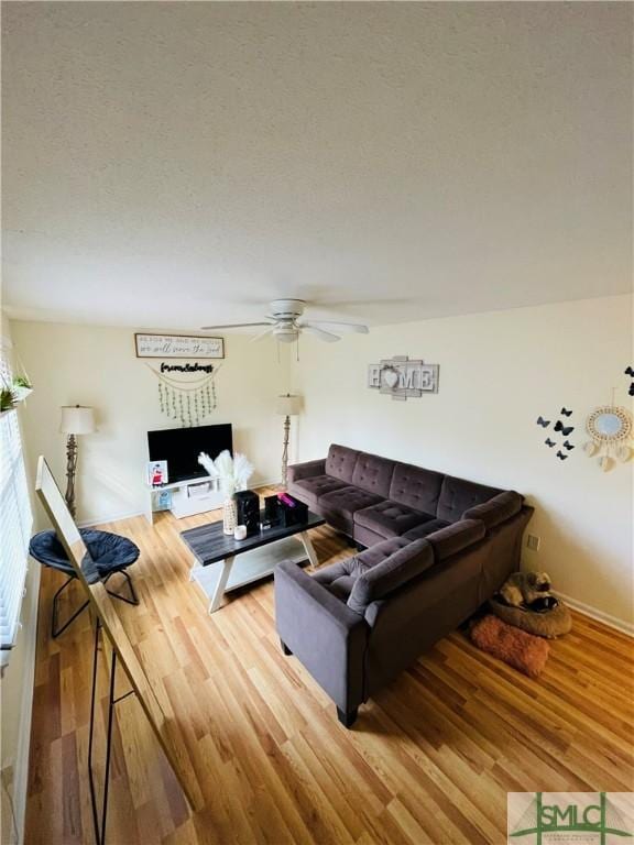 living room featuring ceiling fan, hardwood / wood-style floors, and a textured ceiling