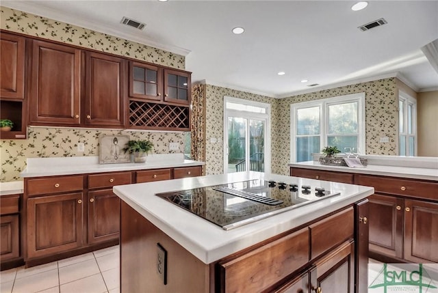 kitchen with crown molding, black electric stovetop, a kitchen island, and light tile patterned floors