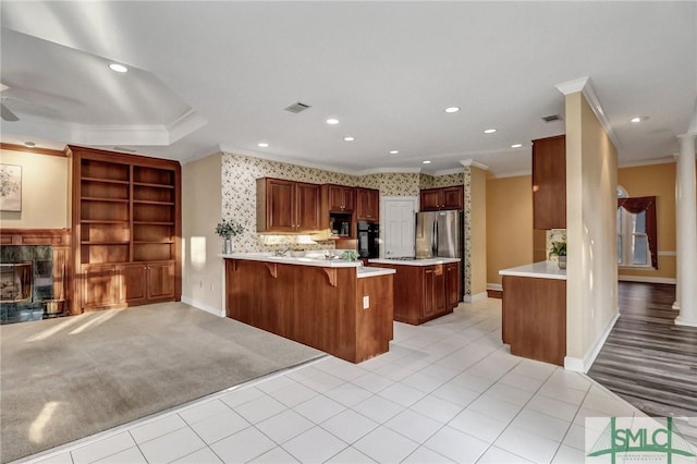 kitchen with a tile fireplace, a breakfast bar, light colored carpet, kitchen peninsula, and crown molding