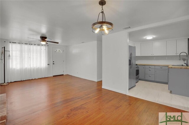 kitchen with appliances with stainless steel finishes, decorative light fixtures, white cabinetry, gray cabinetry, and light hardwood / wood-style floors