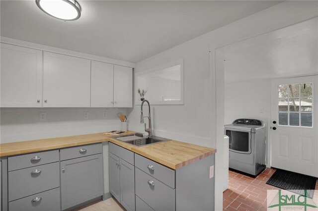 kitchen with butcher block countertops, sink, washer / dryer, and gray cabinets