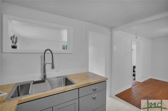 kitchen featuring gray cabinets, sink, and light wood-type flooring