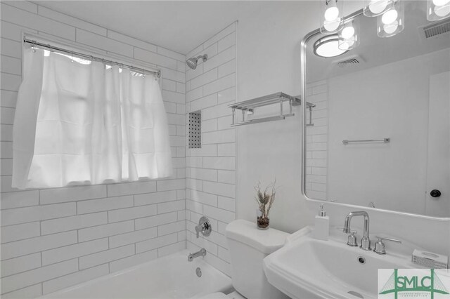 full bathroom featuring tiled shower / bath, toilet, and sink