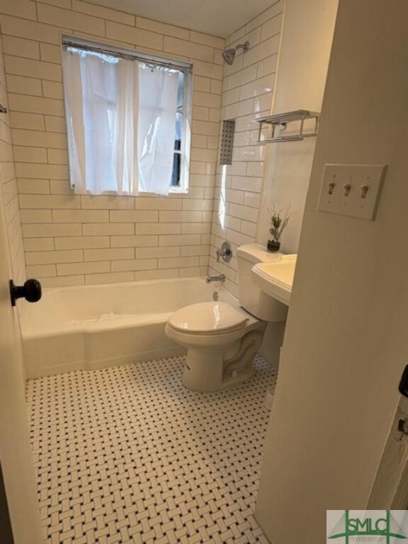 bathroom featuring toilet and tiled shower / bath combo