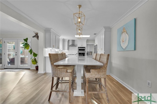 dining area with ornamental molding, light hardwood / wood-style flooring, and french doors