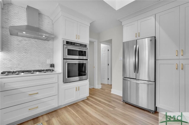 kitchen with light hardwood / wood-style flooring, stainless steel appliances, tasteful backsplash, white cabinets, and wall chimney exhaust hood