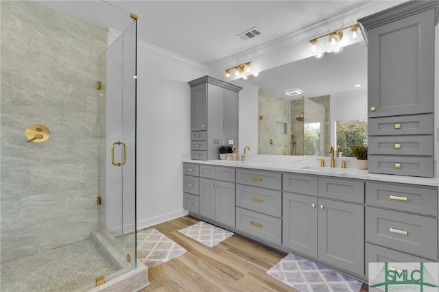 bathroom with ornamental molding, a shower with shower door, hardwood / wood-style floors, and vanity