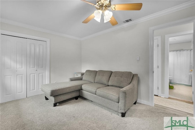 living room with ceiling fan, ornamental molding, and light carpet