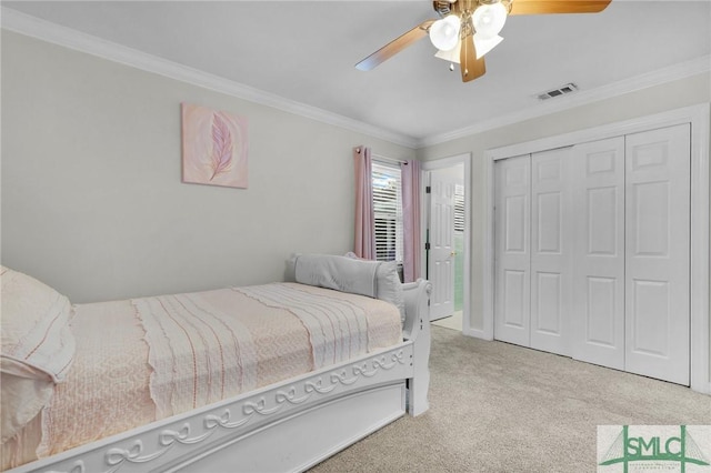 carpeted bedroom with ceiling fan, ornamental molding, and a closet