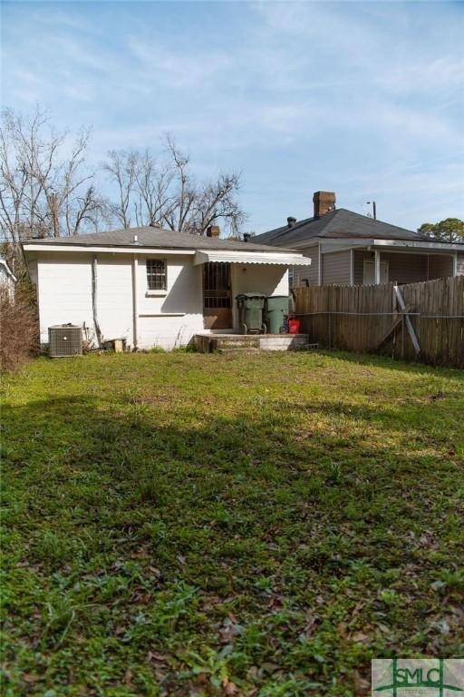 rear view of property featuring a yard and central AC unit