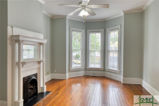 unfurnished living room featuring ceiling fan, ornamental molding, light hardwood / wood-style floors, and a healthy amount of sunlight