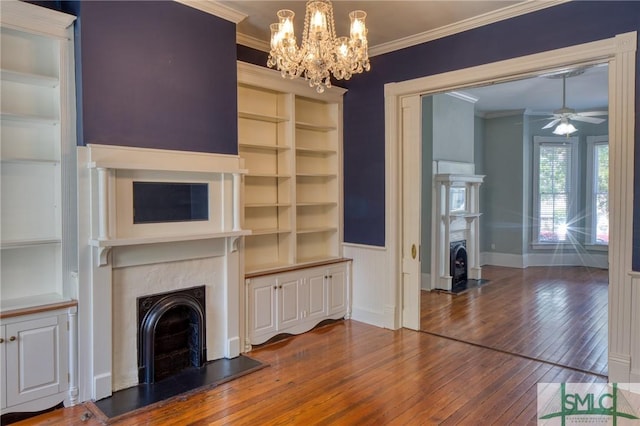 unfurnished living room with ornamental molding, ceiling fan with notable chandelier, hardwood / wood-style floors, and built in features