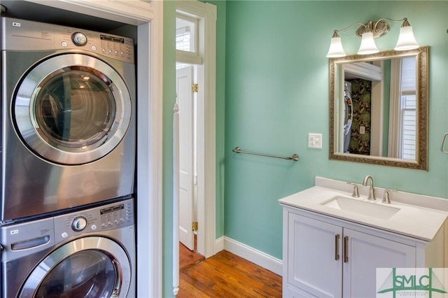 laundry room with hardwood / wood-style flooring, stacked washer / drying machine, and sink