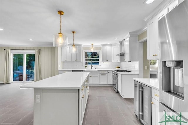 kitchen featuring beverage cooler, light countertops, appliances with stainless steel finishes, and hanging light fixtures