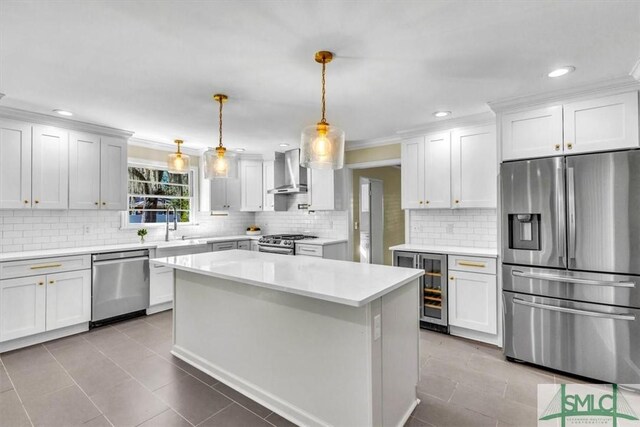 kitchen with pendant lighting, stainless steel appliances, white cabinets, beverage cooler, and wall chimney exhaust hood