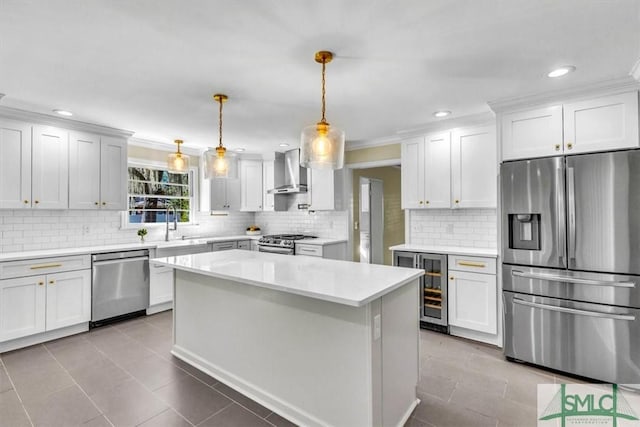 kitchen with white cabinetry, light countertops, appliances with stainless steel finishes, wall chimney exhaust hood, and decorative light fixtures