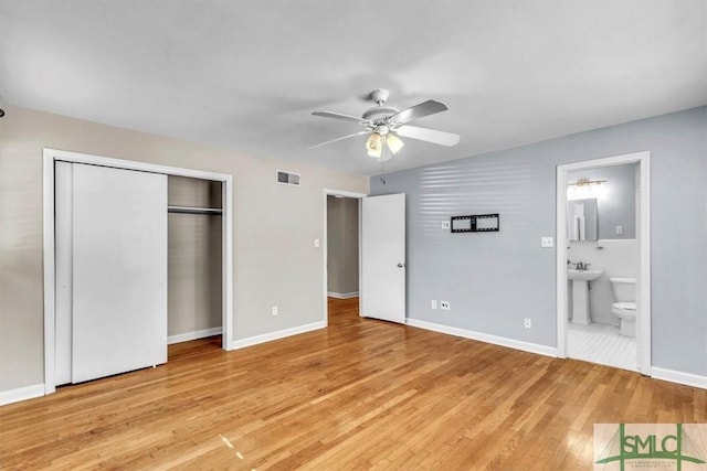 unfurnished bedroom with light wood finished floors, visible vents, a sink, ensuite bath, and baseboards